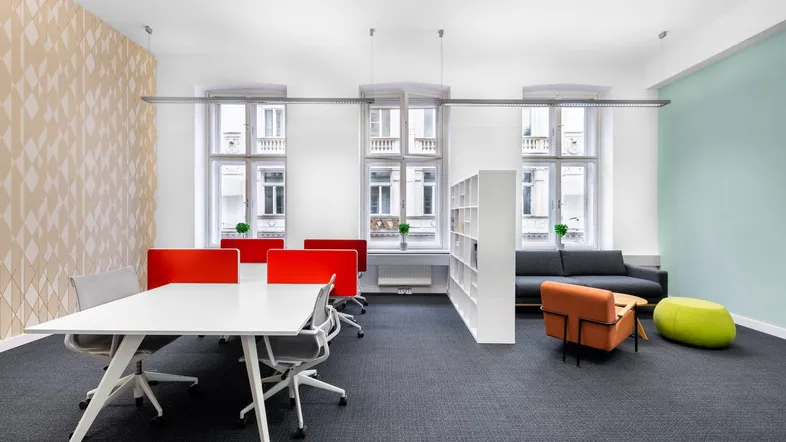 Geräumiger offener Bürobereich mit modernem Design, großen Fenstern und verschiedenen Sitzgelegenheiten.