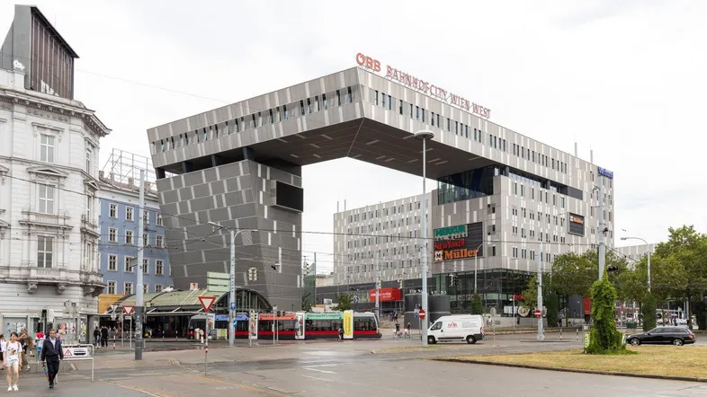 Moderne Architektur des BahnhofCity Wien West Gebäudes mit markantem Bogen über der Straße und umliegender Stadtansicht.