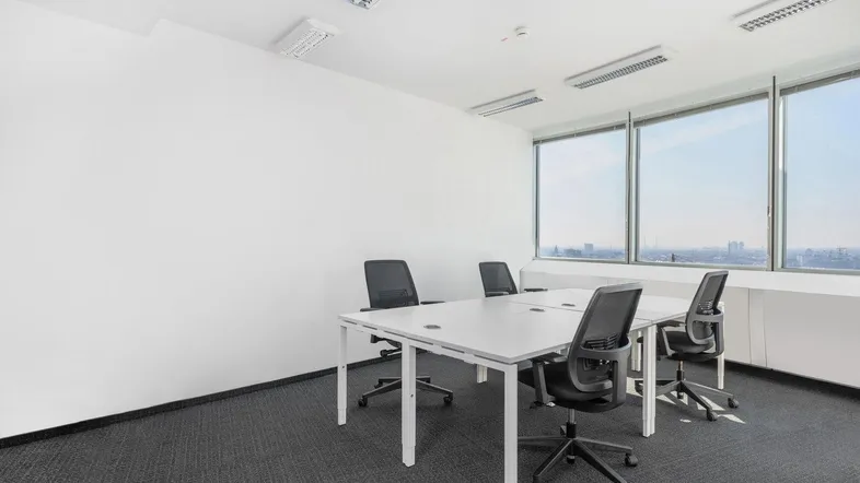 Helles Büro mit modernen Schreibtischen, ergonomischen Stühlen und weitem Blick über die Stadt.