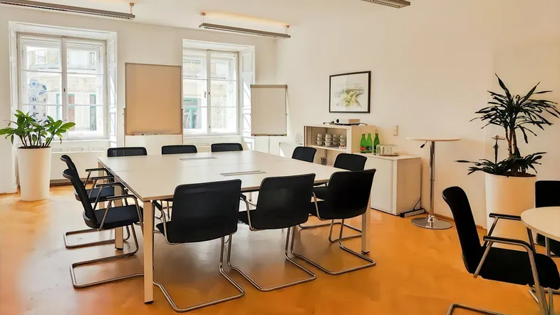 Geräumiger Konferenzraum mit hellem Parkettboden, großen Fenstern und moderner Einrichtung für Besprechungen.