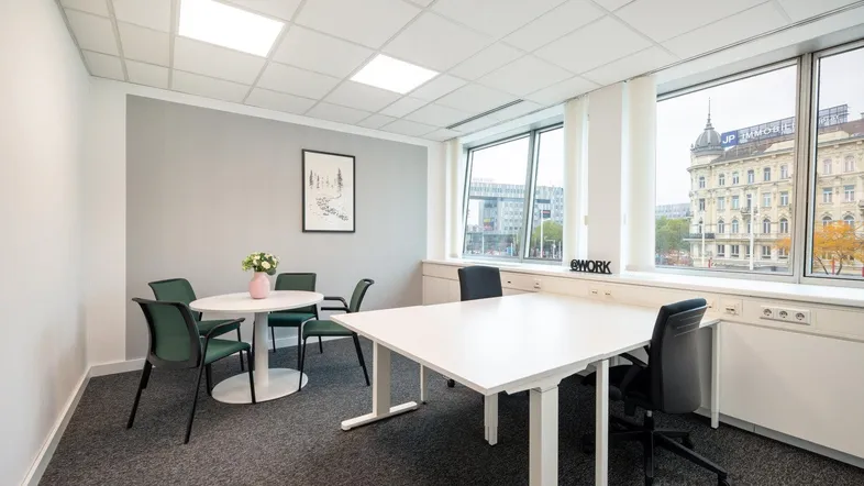 Modernes Büro mit einem Besprechungstisch und großen Fenstern, die viel Tageslicht hereinlassen.