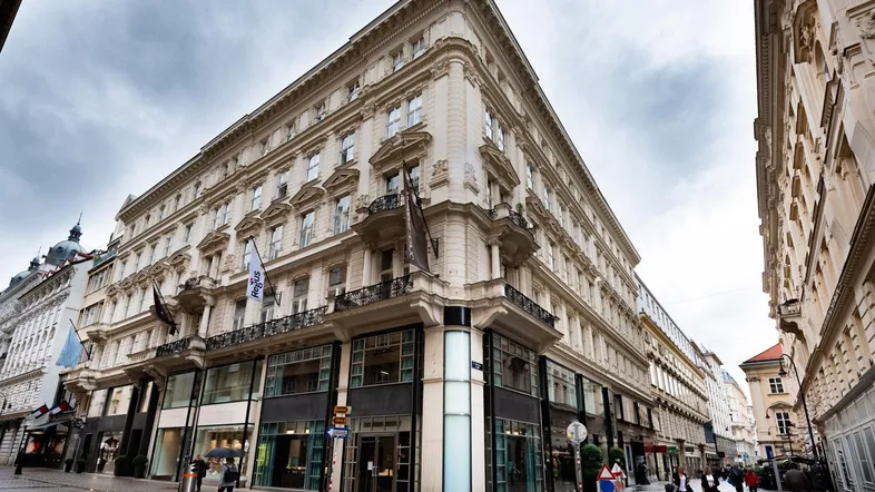 Historisches Gebäude mit klassischer Architektur und Geschäften im Erdgeschoss an einer belebten Straße.