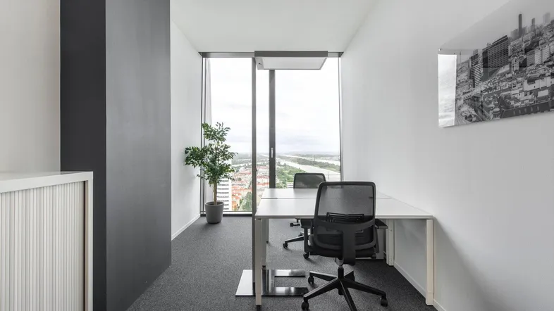 Modernes Büro mit Schreibtisch, Bürostuhl und großen Fenstern, die einen weiten Blick auf die Stadt und den Fluss bieten.