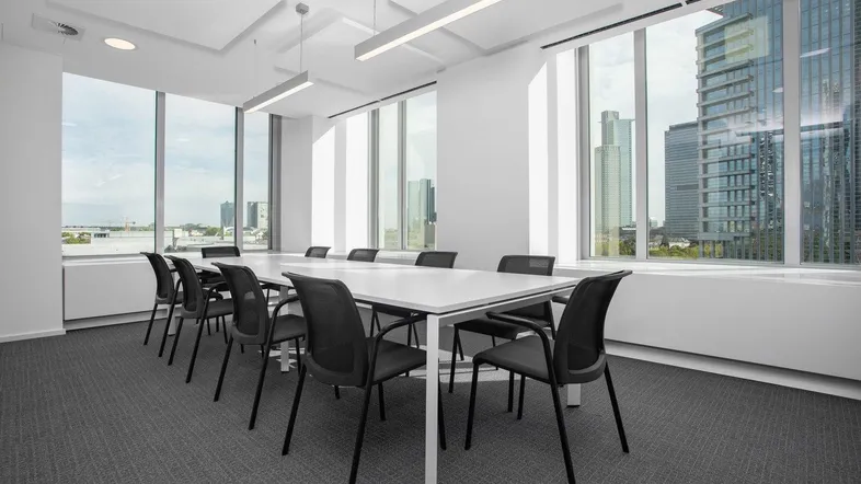 Heller Konferenzraum mit großen Fenstern, die einen weiten Blick auf die Stadt und moderne Gebäude bieten.