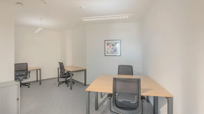 Helles Büro mit mehreren Arbeitsplätzen, grauen Teppichböden und weißen Wänden für produktives Arbeiten.