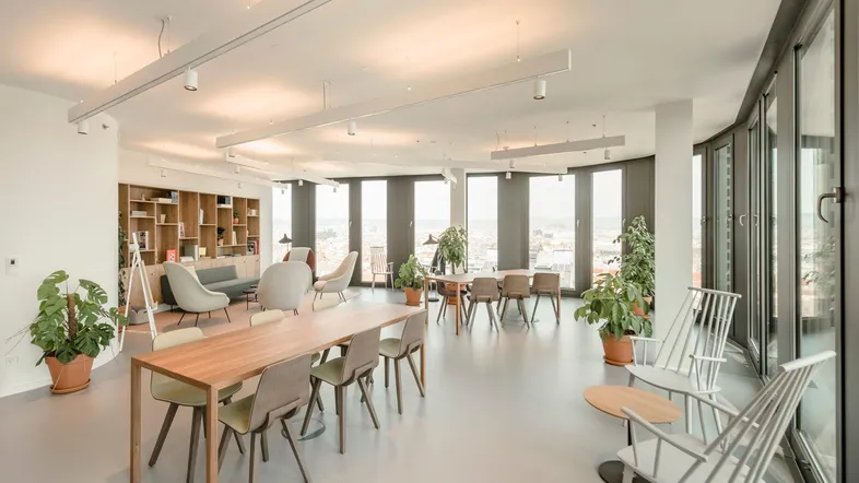 Großer, offener Bürobereich mit verschiedenen Sitzgelegenheiten, langen Tischen und Bücherregalen, bietet einen weiten Stadtblick.