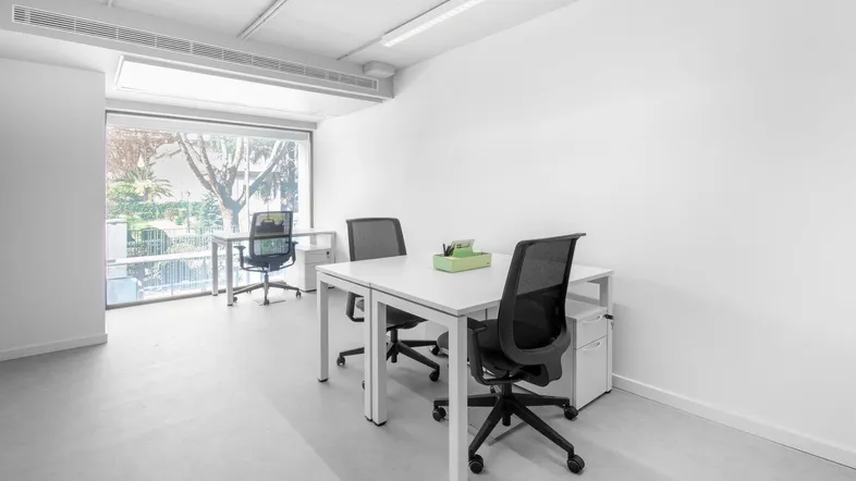 Helles und modernes Büro mit großen Fenstern, die viel Tageslicht hereinlassen und einen Blick ins Grüne bieten.