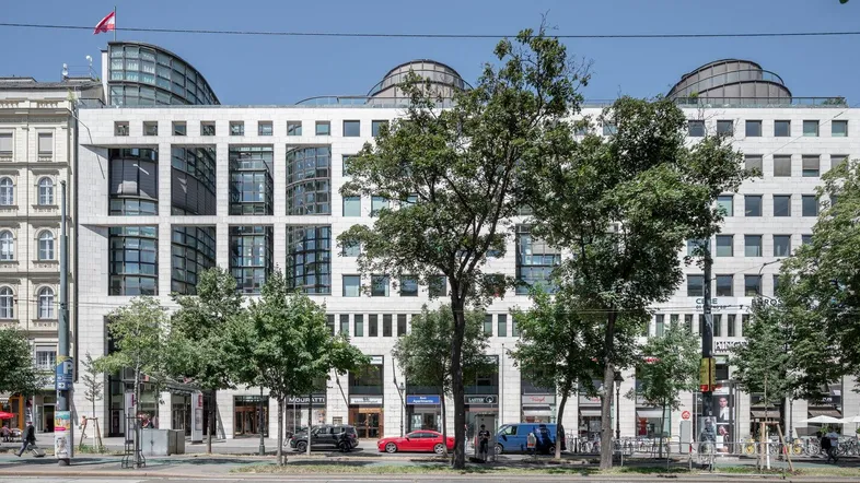 Modernes Bürogebäude mit markanter Fassade und geschwungenen Dächern an einer belebten Straße.