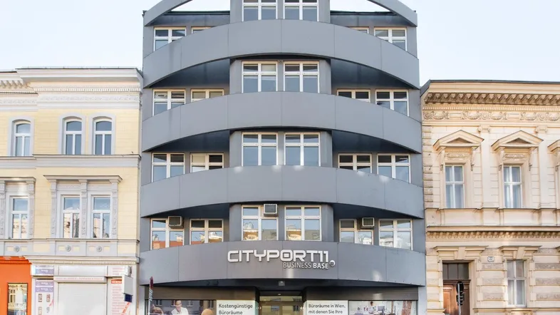 Modernes Bürogebäude mit geschwungener Fassade und großen Fenstern in urbaner Umgebung.