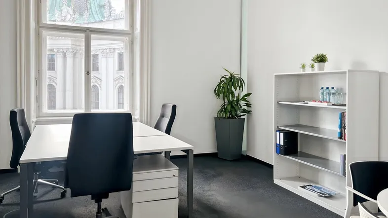Helles Büro mit großem Fenster, Blick auf ein historisches Gebäude und moderner Einrichtung.