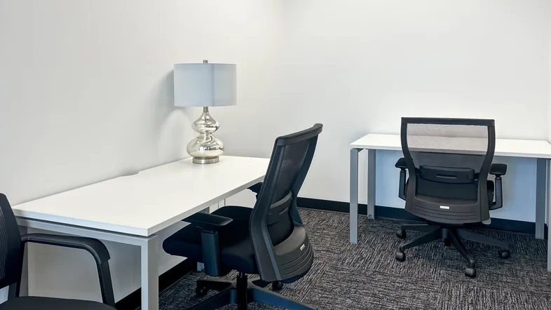 Helles Büro mit zwei Arbeitsplätzen, modernen Schreibtischen und ergonomischen Bürostühlen.