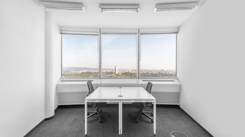 Helles Büro mit zwei Arbeitsplätzen und großen Fenstern, die einen weiten Blick über die Stadt bieten.