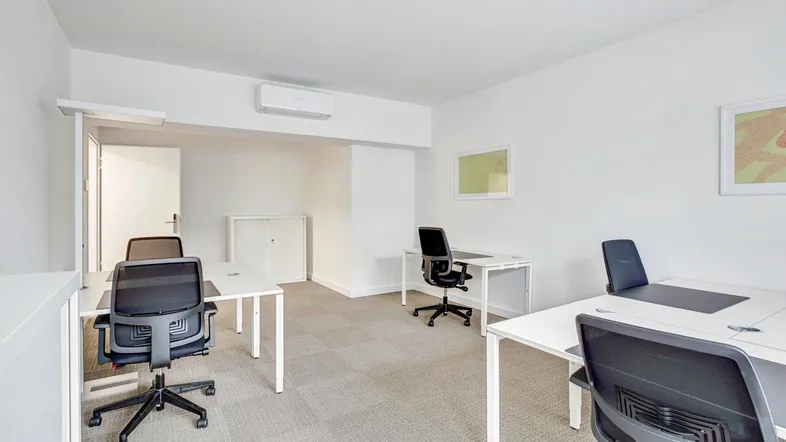 Helles, modernes Büro mit mehreren Arbeitsplätzen, Teppichboden und Klimaanlage.