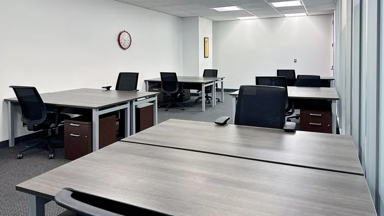 Heller Büroraum mit mehreren Schreibtischen und Bürostühlen, ideal für Coworking-Spaces.