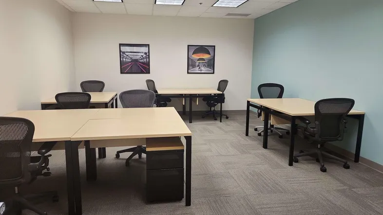 Geräumiges Büro mit mehreren Schreibtischen und Bürostühlen, ideal für einen modernen Arbeitsbereich mit Teppichboden.