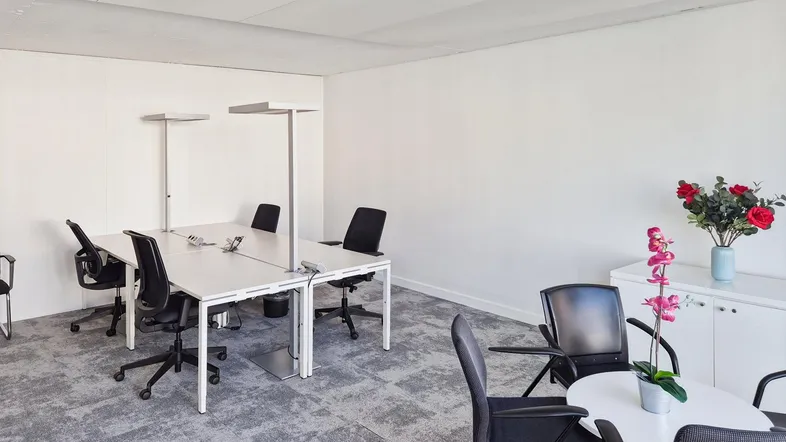Heller Büroraum mit modernen Schreibtischen, ergonomischen Stühlen und Teppichboden für effizientes Arbeiten.