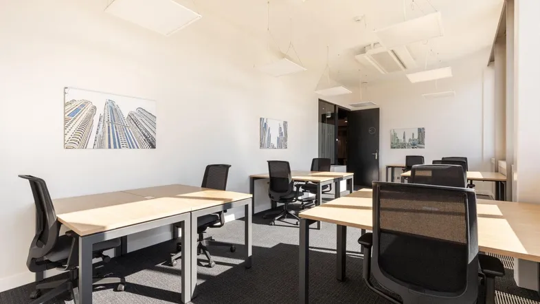 Heller und moderner Großraumbüro-Arbeitsbereich mit mehreren Schreibtischen und ergonomischen Stühlen.