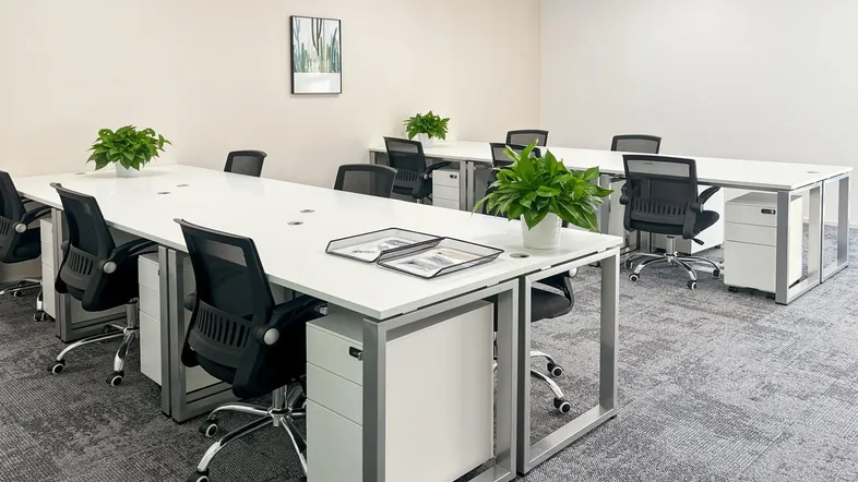 Moderner Großraumbüro-Arbeitsbereich mit mehreren Schreibtischen, ergonomischen Stühlen und Teppichboden.