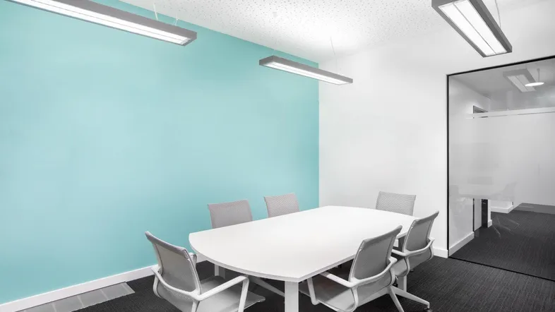 Moderner Konferenzraum mit hellblauer Akzentwand, großem Tisch und ergonomischen Stühlen für Besprechungen.