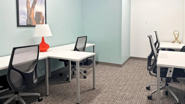 Helles Büro mit mehreren Arbeitsplätzen, Schreibtischen und Bürostühlen, ideal für konzentriertes Arbeiten.