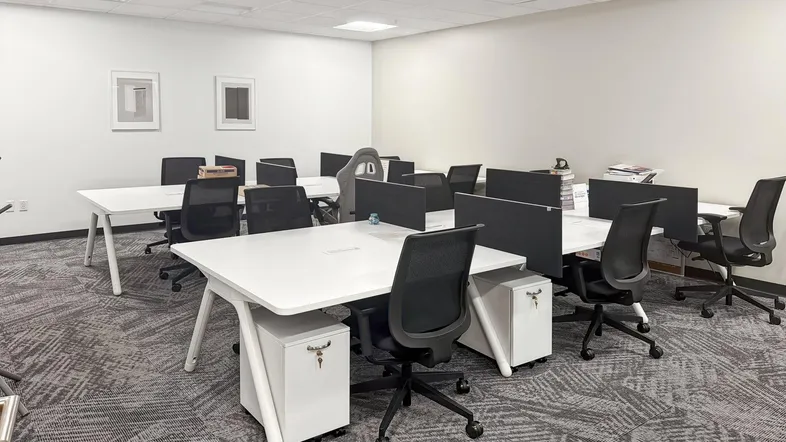 Geräumiges Großraumbüro mit modernen Schreibtischen, ergonomischen Stühlen und gemustertem Teppichboden.