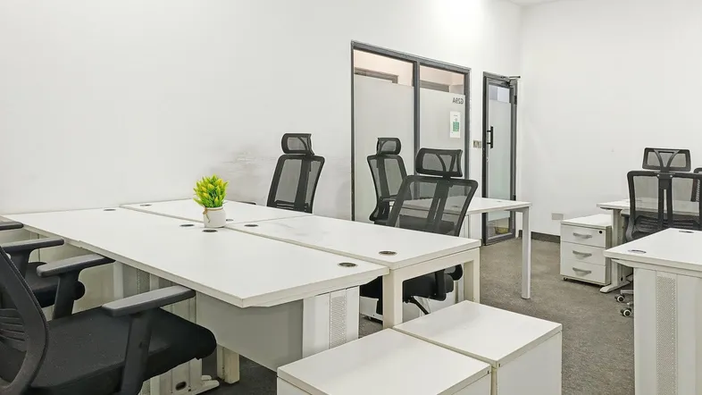 Moderner Büroraum mit mehreren Arbeitsplätzen, weißen Tischen und ergonomischen Stühlen.