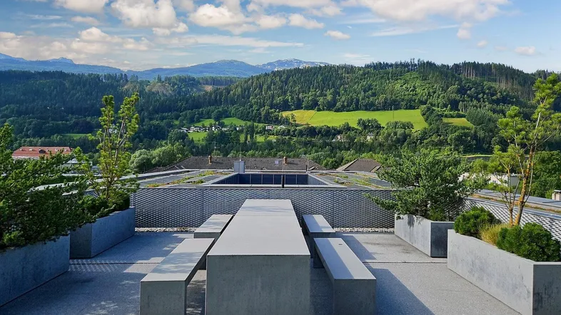 Große Dachterrasse mit modernen Sitzgelegenheiten und weitem Blick auf grüne Hügel und Berge.