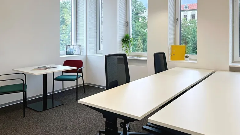 Helles Büro mit mehreren Arbeitsplätzen, großen Fenstern und Blick ins Grüne.