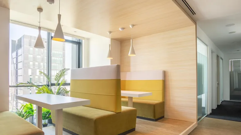 Moderner Bürobereich mit gemütlichen Sitznischen, Holzelementen und Blick auf die Stadt.