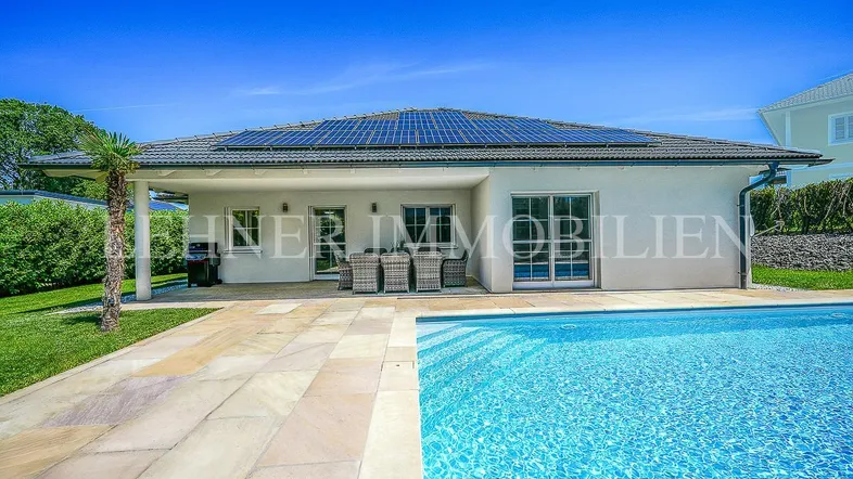 Modernes Einfamilienhaus mit Pool und Sonnenterrasse, umgeben von einem gepflegten Garten.
