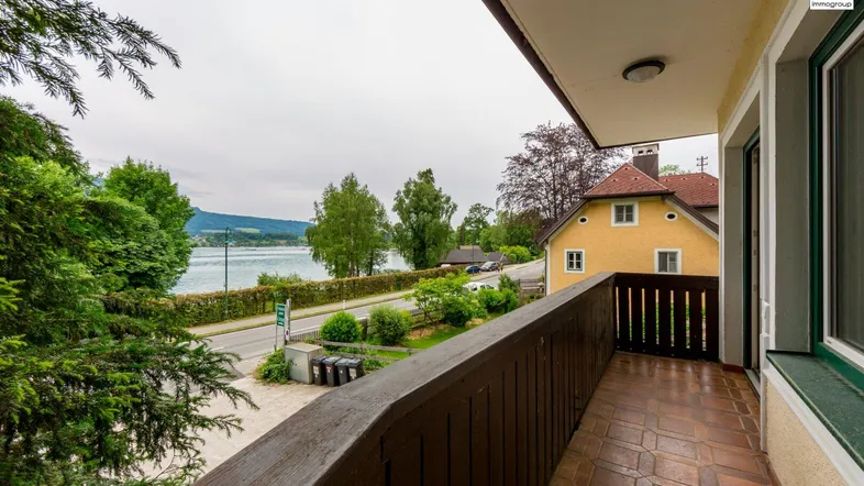 Balkon mit Holzboden und Geländer, bietet einen weiten Blick auf den See und die umliegende Landschaft.