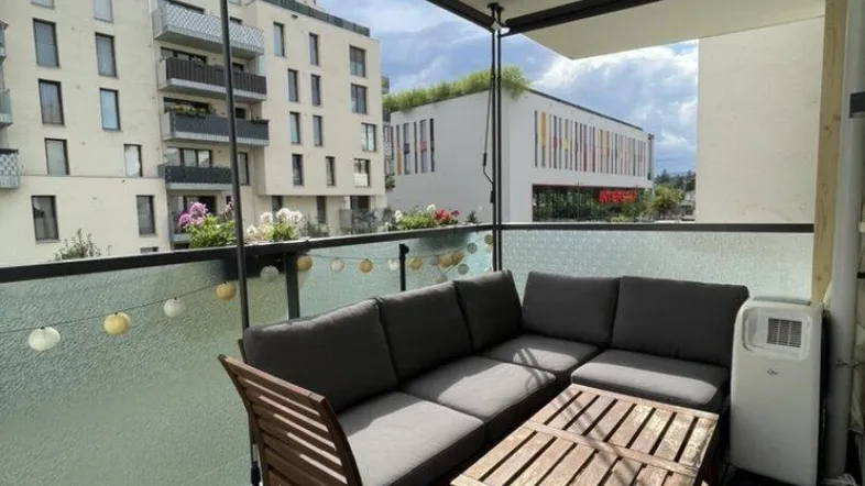Gemütlicher Balkon mit Holzsitzgruppe und Fliesenboden, ideal für entspannte Stunden im Freien.