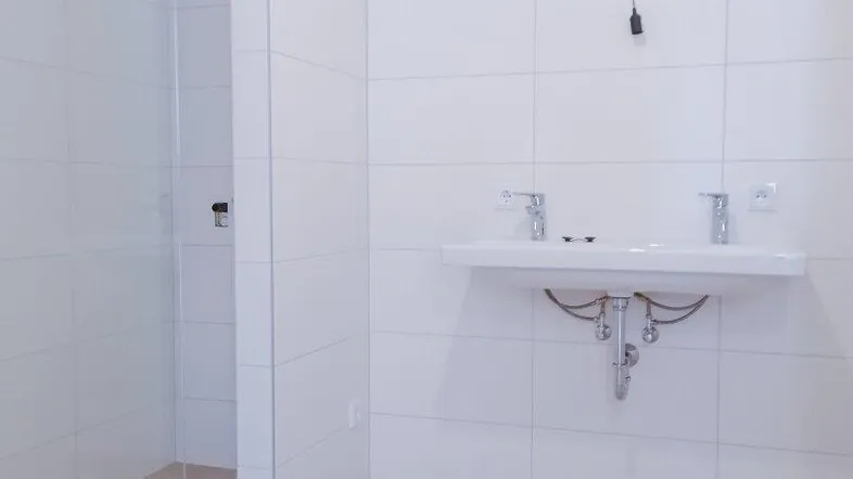 Modernes Badezimmer mit Doppelwaschbecken und begehbarer Dusche, hell gefliest.