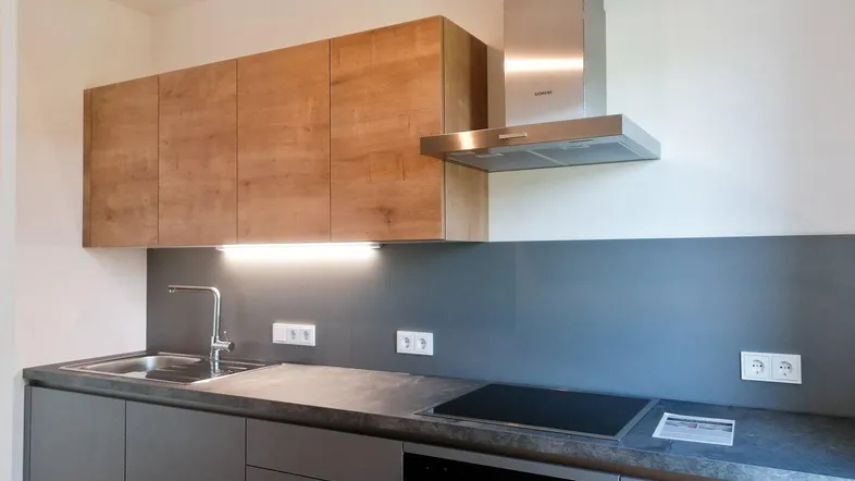 Moderne Küche mit Holz- und Grautönen, ausgestattet mit Kochfeld und Dunstabzugshaube.