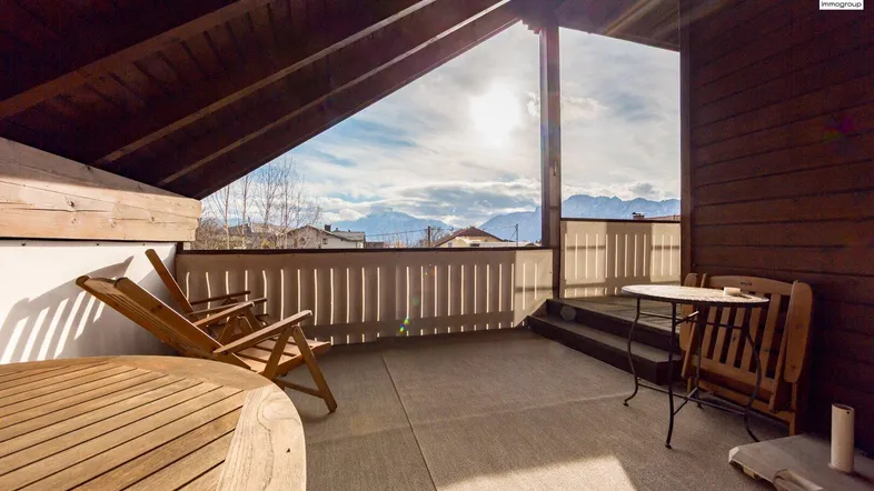 Geräumige überdachte Terrasse mit Holzboden, Sitzgelegenheiten und weitem Blick auf die Berge.