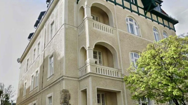 Historisches Mehrfamilienhaus mit markanter Fassade, mehreren Balkonen und Loggien.