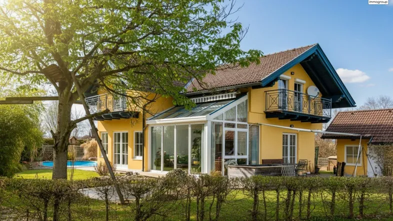 Großzügiges Einfamilienhaus mit gelber Fassade, Wintergarten, Balkonen und einem weitläufigen Garten mit Pool.