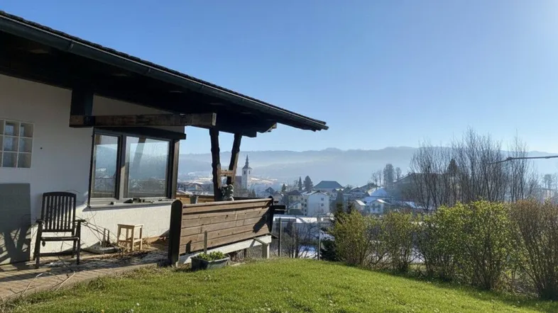 Terrasse mit Rasenfläche und weitem Blick über die Stadt und die umliegenden Berge.