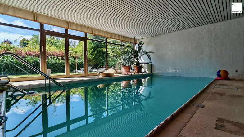 Helles Hallenbad mit großen Fenstern, die einen Blick in den grünen Garten bieten.