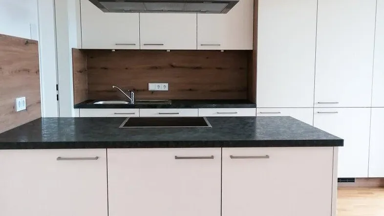 Moderne Küche mit weißer Kücheninsel, dunkler Arbeitsplatte und Holzakzenten.