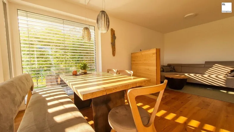 Heller Wohn- und Essbereich mit Holztisch, bequemer Sitzbank und viel natürlichem Licht.