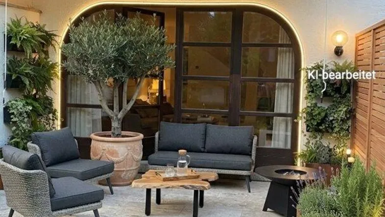 Gemütliche Terrasse mit bequemen Loungemöbeln, einem Olivenbaum und einem Balkon darüber.