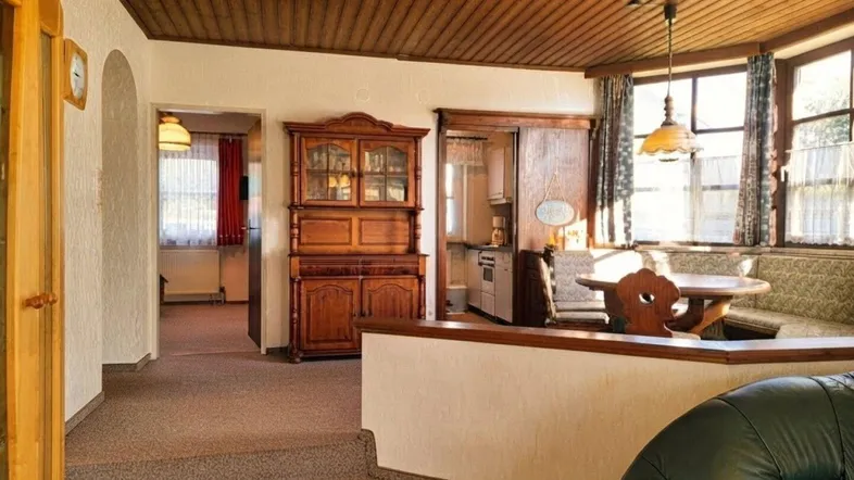 Gemütlicher Wohn- und Essbereich mit Holzdecke, Teppichboden und traditionellen Holzmöbeln.