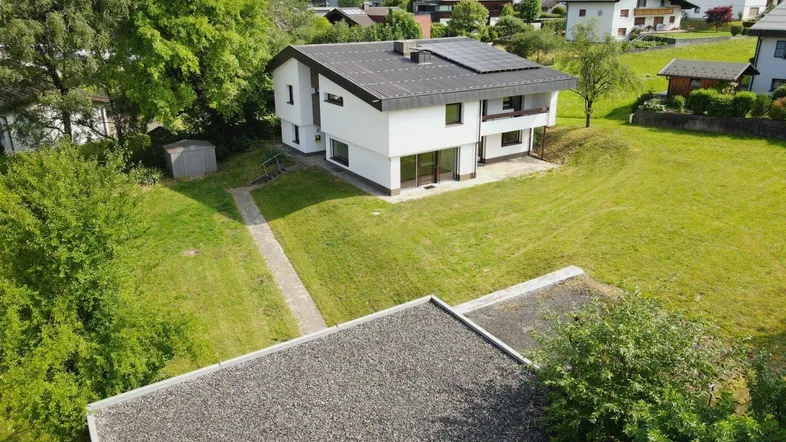 Modernes Einfamilienhaus mit Photovoltaikanlage auf dem Dach und großem Garten in ländlicher Umgebung.