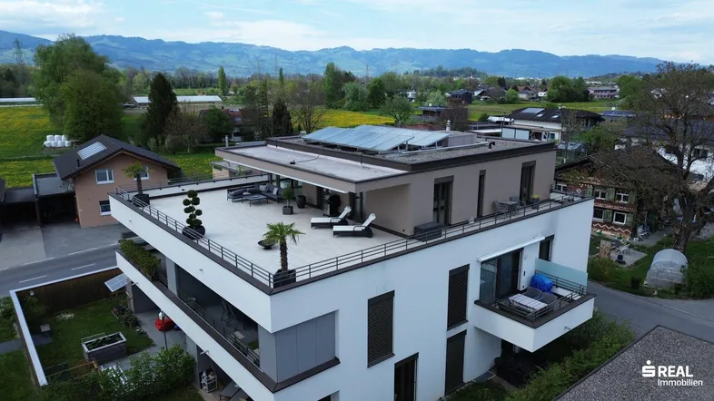 Luftaufnahme der modernen Wohnanlage mit Dachterrassen und Photovoltaikanlage in ländlicher Umgebung.