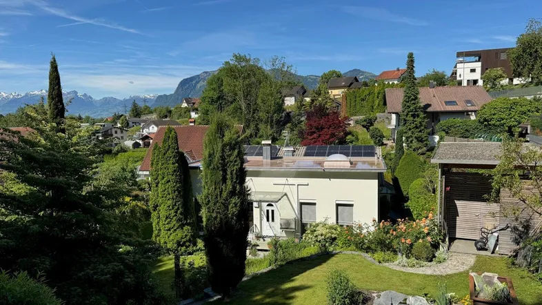 Weitläufiger Blick über die Nachbarschaft mit Bergen im Hintergrund und Solaranlagen auf dem Dach.