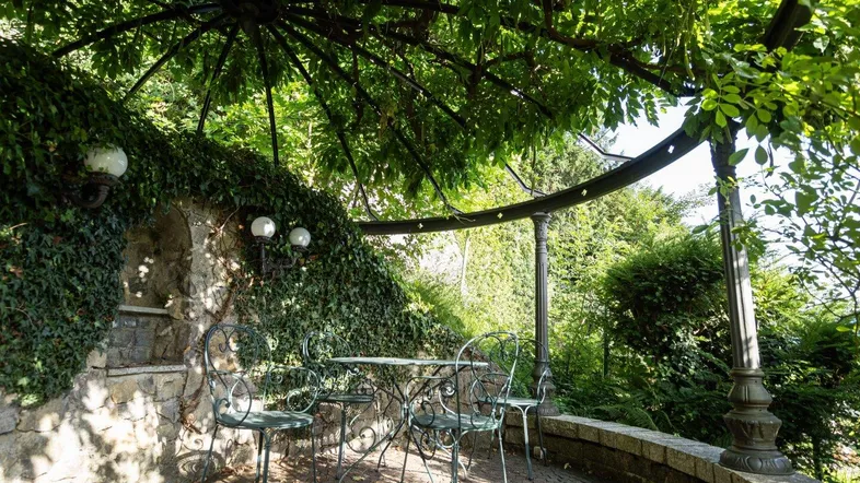 Gemütlicher Sitzplatz im Freien unter einer grünen Pergola, ideal für entspannte Stunden.