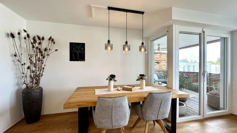 Moderner Essbereich mit Holztisch, bequemen Stühlen und Zugang zum Balkon.