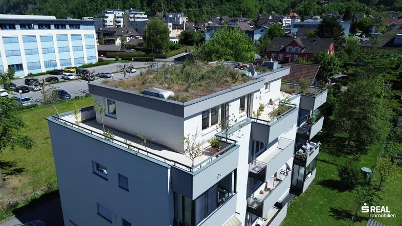 Moderne Wohnanlage mit begrüntem Flachdach und mehreren Balkonen in einer grünen Umgebung.
