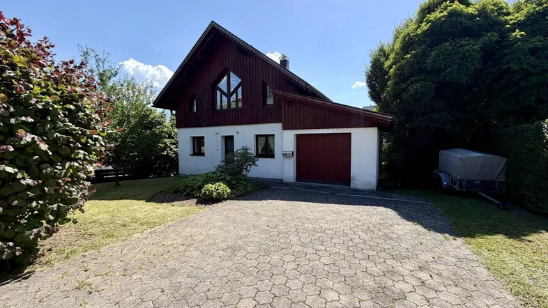 Vorderansicht des Einfamilienhauses mit Satteldach, Garage und gepflasterter Auffahrt.
